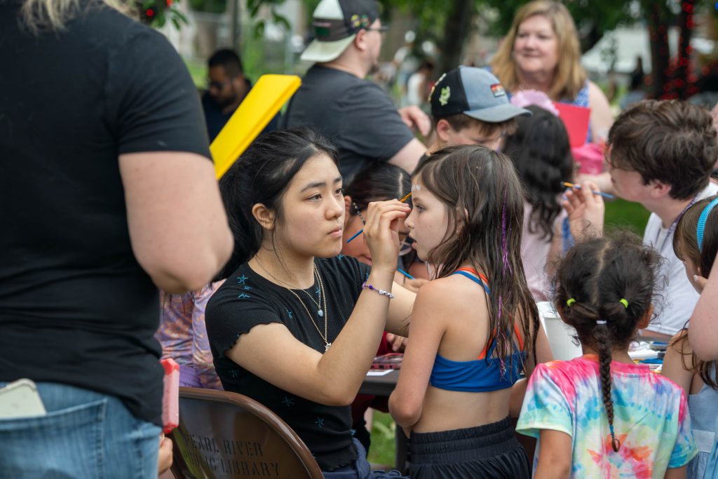 A girl receives face painting at a community event