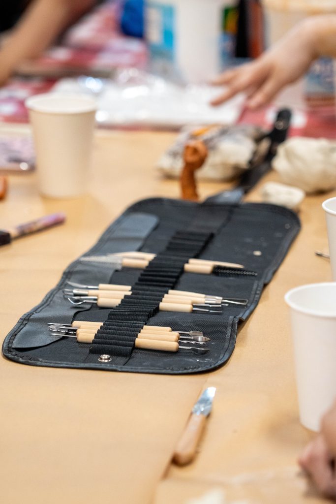 Clay sculpting tools arranged on a table with cups nearby