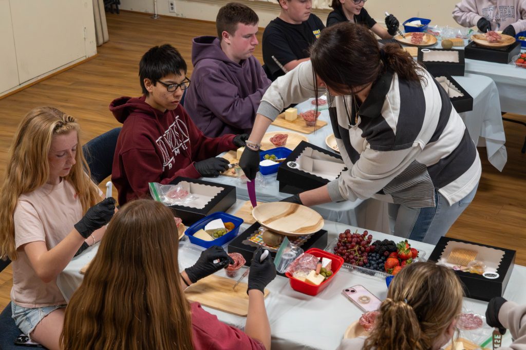 Students create charcuterie boards with guidance from an instructor