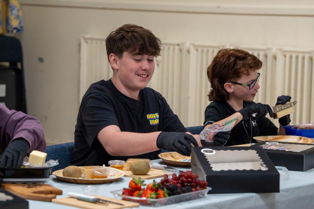 Two young people preparing charcuterie boards with various ingredients