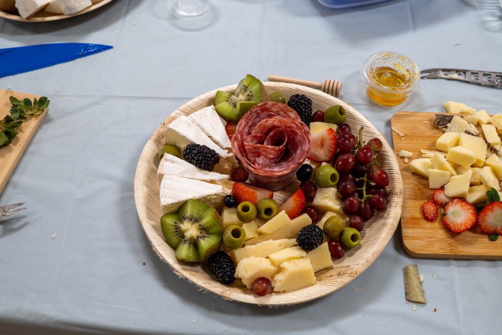 A wooden platter filled with assorted cheeses fruits and meats