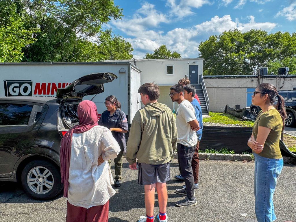 A group of people gathered around a car's open trunk
