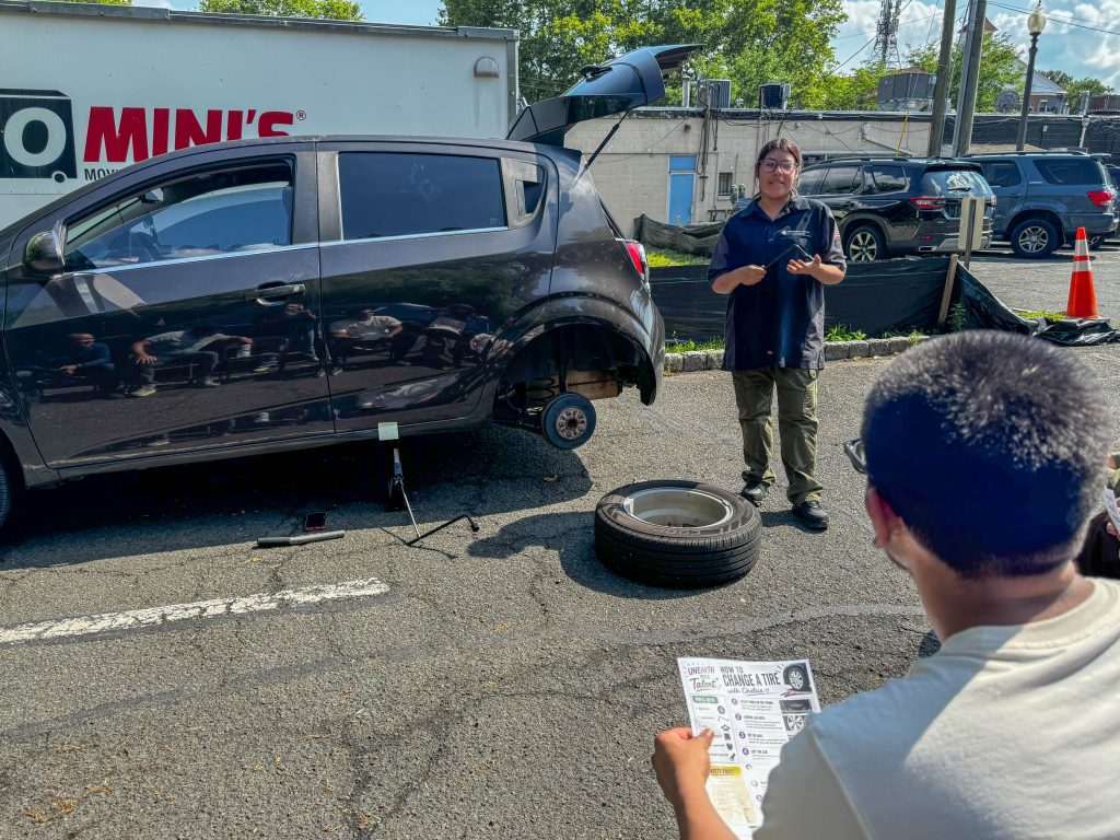 A person teaches tire-changing skills to an attentive audience